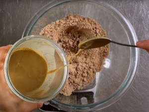 Stir in the date syrup, tahini, and plant‑based milk until the mixture starts to come together.