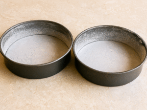 Preheat oven to 350°F (175°C). Line the bottoms of two deep 8‑inch round cake pans with parchment paper, then lightly grease and flour the sides.
